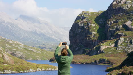 Rear-view-of-a-young-woman-using-a-smartphone-to