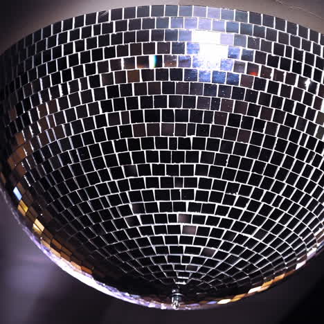 turning mirror disco ball against dark background. joy, dancing or party concepts. spinning mirror disco ball on the ceiling. close-up.
