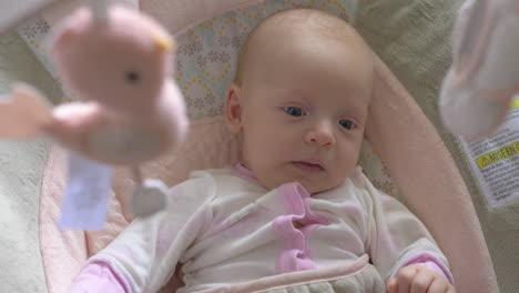 two months old baby girl under the baby mobile