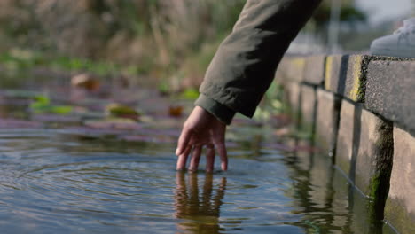 Nahaufnahme-Einer-Frau,-Die-Mit-Der-Hand-Wasser-Spritzt-Und-Das-Berühren-Eines-Frischen-Teichs-Im-Naturpark-Im-Freien-Genießt