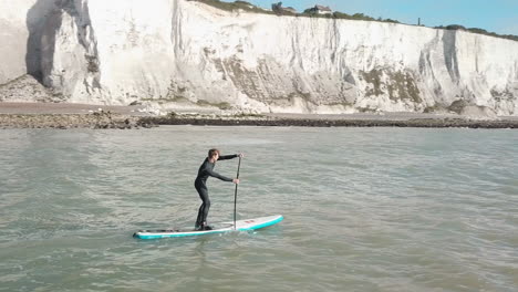 young man stand up paddle boarding in the sea