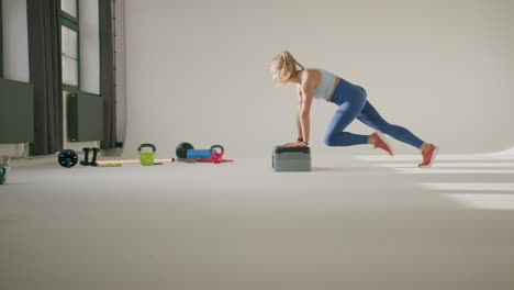 fit girl doing mountain climbers, hands on aerobic step