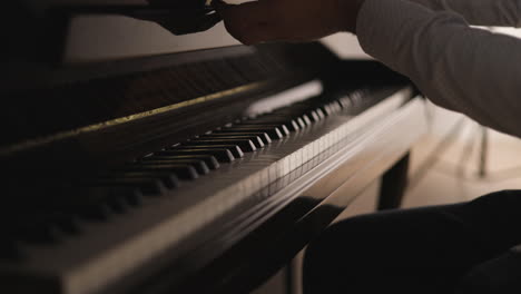 pianist’s hands playing the final note of a song and carefully closing the fallboard of his piano