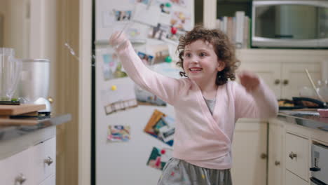 happy little girl dancing in kitchen having fun waving maginc wand playing pretend doing funny dance moves enjoying weekend at home