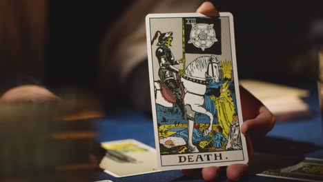 close up of woman giving tarot card reading on candlelit table holding death card 3