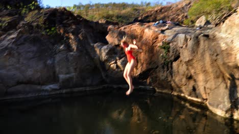 Girl jumping into a lake. Wide shot.