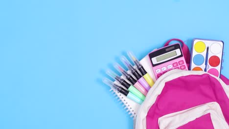 school backpack with school stationery move on blue background. stop motion