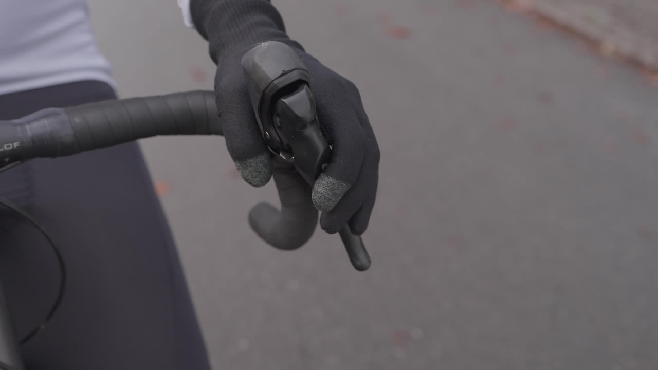 Primo piano di una mano guantata appoggiata alla leva del freno di una bici da corsa durante una pausa in bicicletta all'aperto.