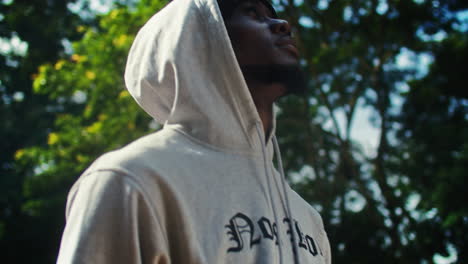 Side-portrait-of-young-black-man-in-gray-hoodie-outdoors,-tilt-down