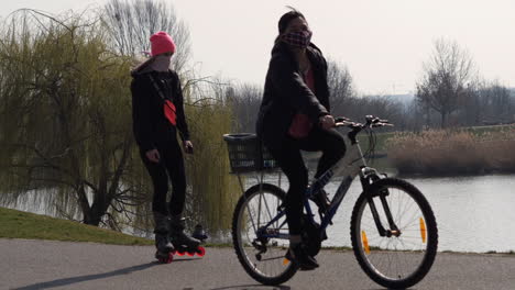 people with face mask on everyday outdoor activity, riding bicycle and rollers. covid-19 virus pandemic and new normal concept, slow motion