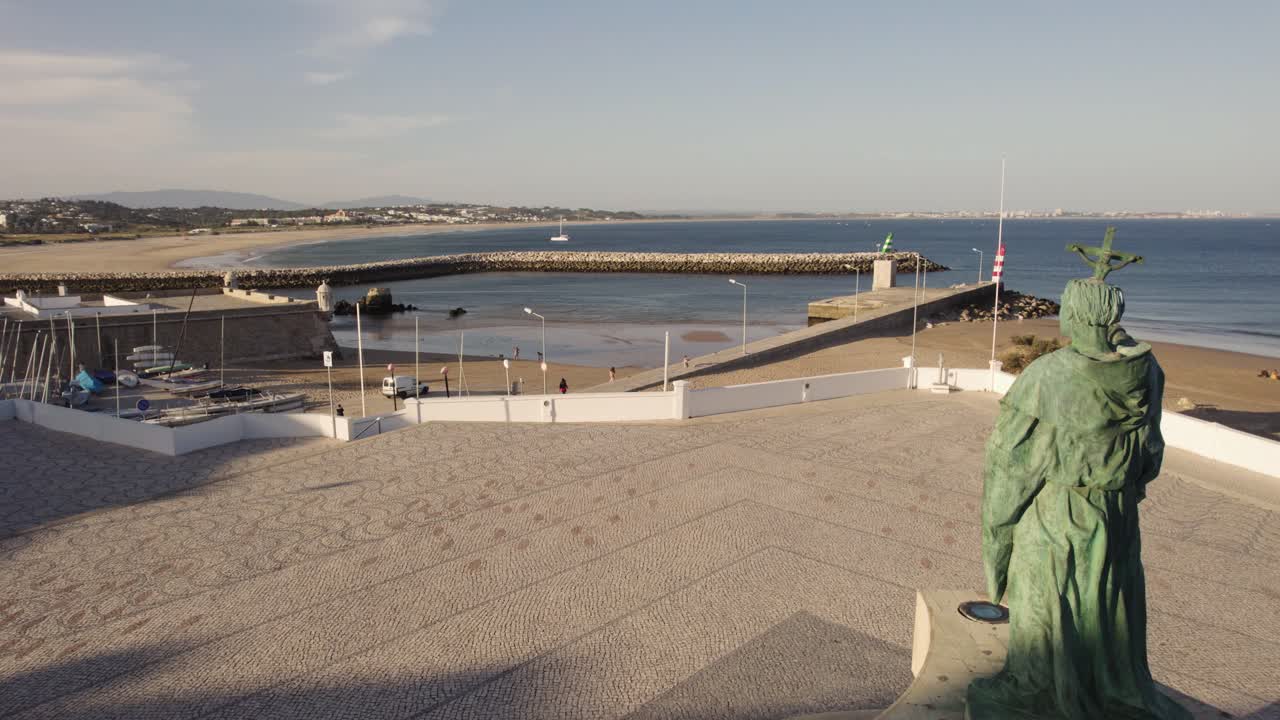 Statua di São Gonçalo de Lagos sullo sfondo della foce del fiume e della spiaggia, Algarve, Portogallo.