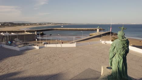 estatua de são gonçalo de lagos contra la desembocadura del río y la playa, algarve, portugal