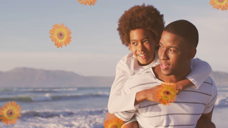 animation of flowers over happy african american father with son on sunny beach