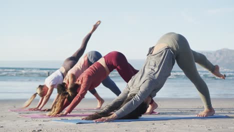 Group-of-diverse-female-friends-practicing-yoga-at-the-beach