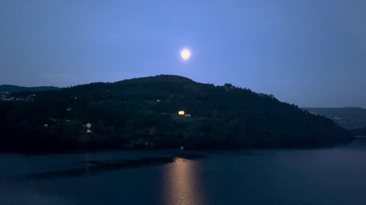 Vista aerea della luna piena che sorge su un'enorme montagna nel fiume Douro con un grande riflesso sull'acqua, Portogallo.