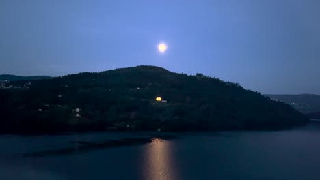 aerial view of full moon rising over huge mountain in river douro with a huge reflexion on water, portugal