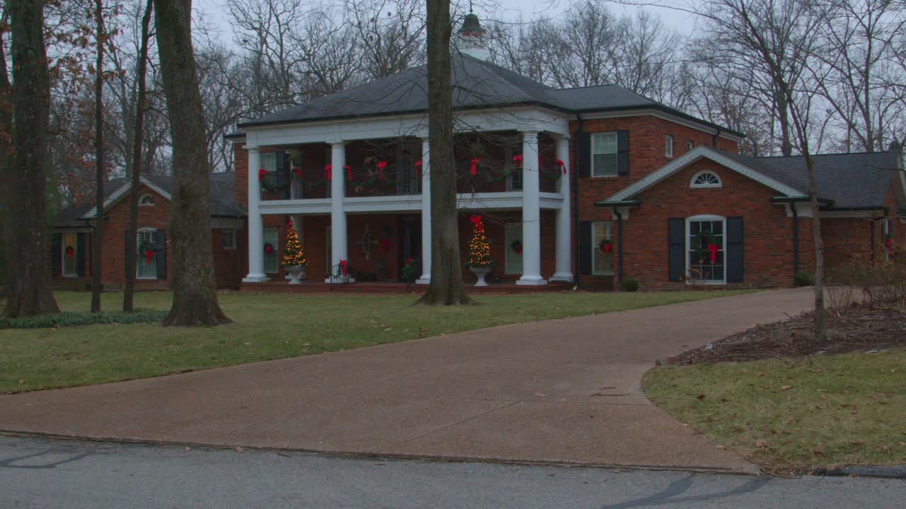 Shot from right to left of Fortuna Missouri homestead beautifully decorated with red bows and Christmas trees in rural Missouri, USA during a cloudy day