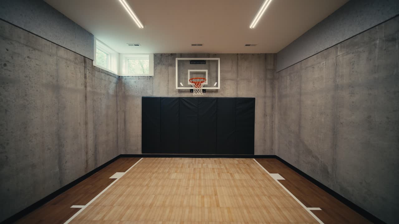 en un tiro de un en una cancha deportiva cubierta dentro de una casa de lujo con una cancha de baloncesto y un aro