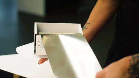 tattooed hairdresser is cutting sheets of foil from dispenser. getting ready to dye clients hair. slow motion.