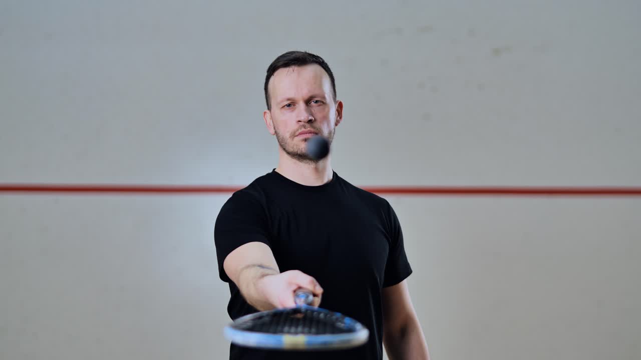 Slow motion focus shift from face to ball bouncing on racket in squash court
