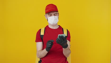 male courier wearing protective face mask using smartphone and showing device with green chroma key screen