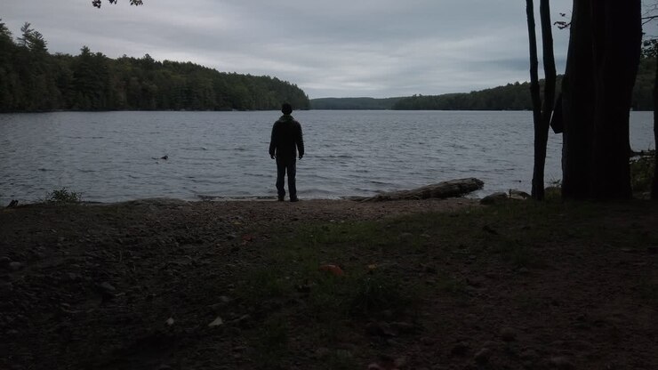 Male figure standing on the shoreline at MacDonald Lake