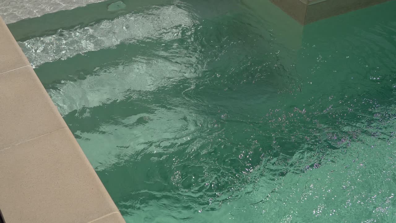 Clear water rippling in a swimming pool, reflecting sunlight.