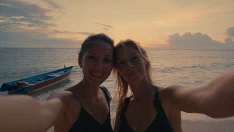two friends taking a selfie at sunset on the beach