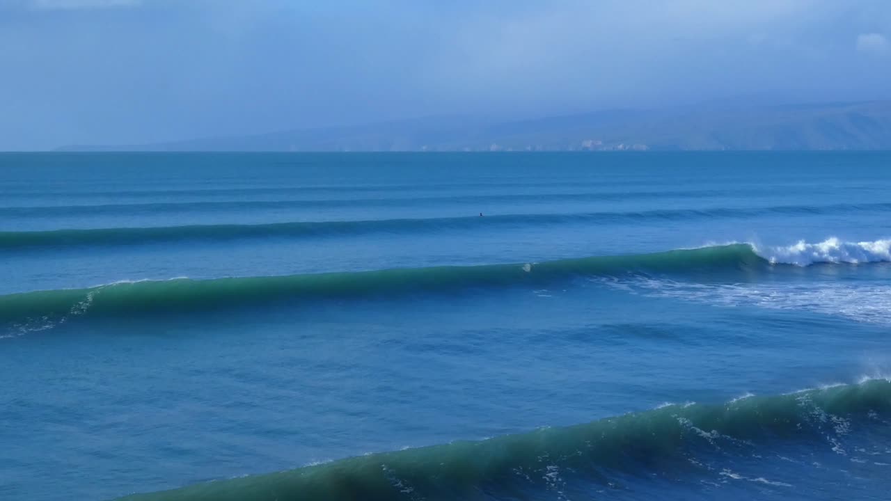 Lone surfer waiting for wave is just visible on a beautiful mid-winter's morning - New Brighton Beach, Christchurch (New Zealand)