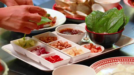 hands assembling miang kham with fresh ingredients on a table in phuket. bright lighting enhances the vibrant colors of the dish