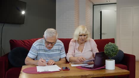 a senior couple argues about finances in their living room