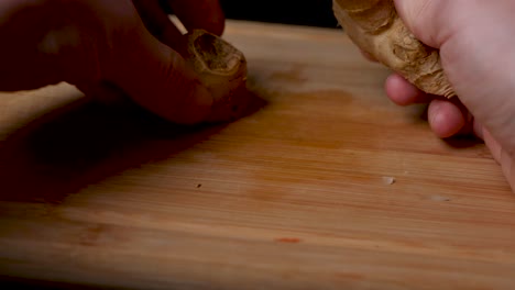 cortar un tubérculo de jengibre en una tabla de cortar de madera