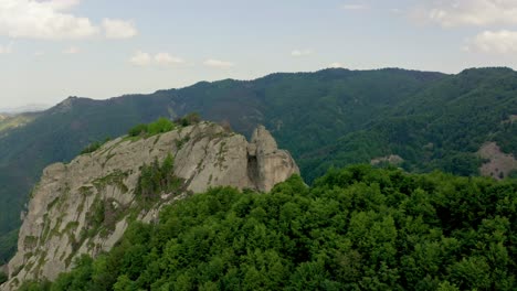 Toma-Aérea-Acercándose-A-La-Famosa-Roca-Karadzhov-En-Las-Montañas-Ródope-Durante-El-Día-Soleado---Turista-Parado-En-El-Borde