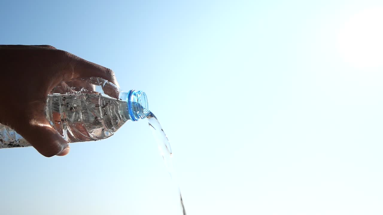 vertiendo agua de una botella de plástico en un día soleado