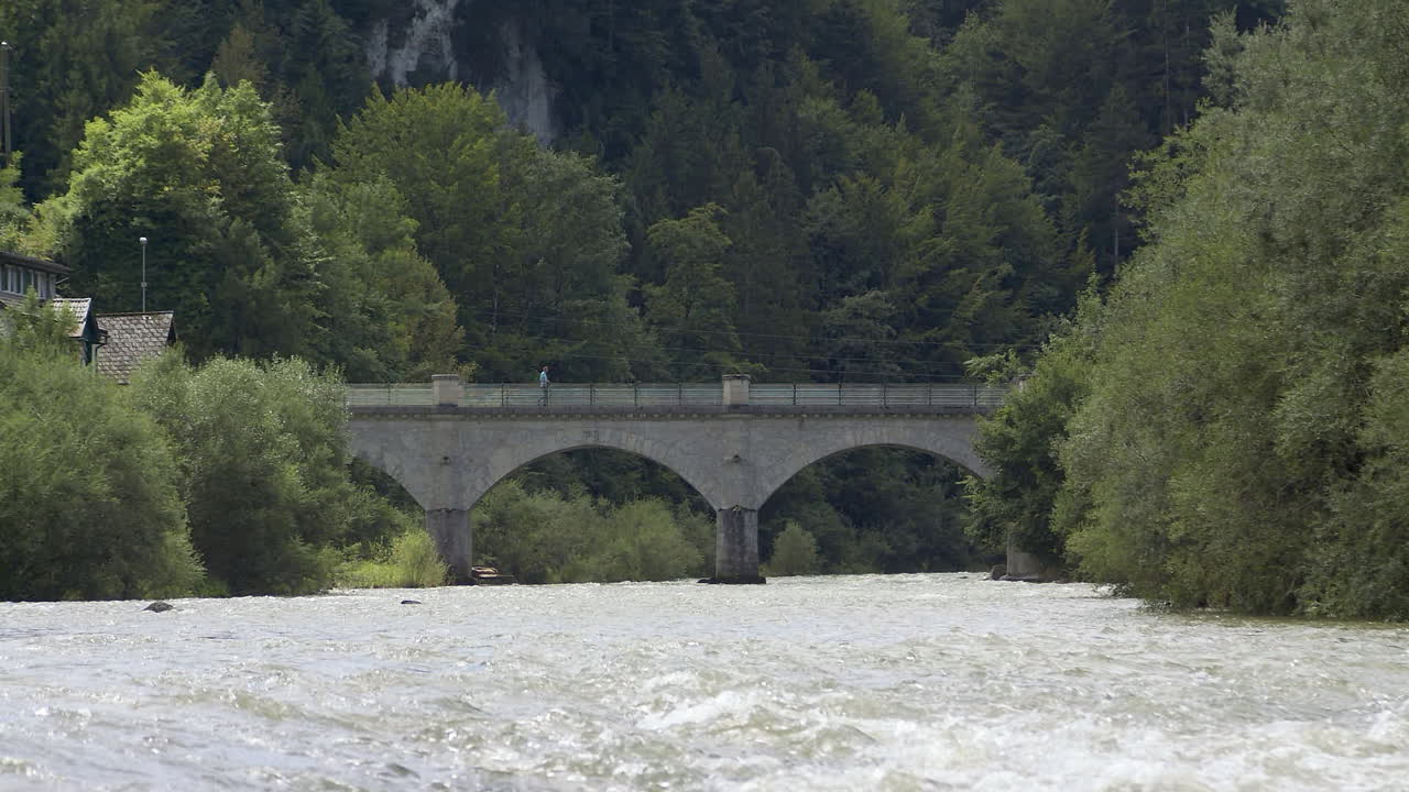 hombre camina sobre un puente, puente de piedra histórico sobre un río pintoresco