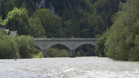 man walks over a bridge, historic stone bridge over a picturesque river