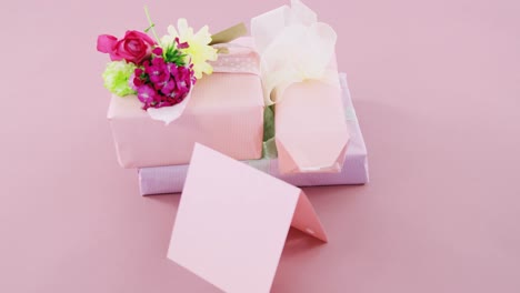 gift boxes with flowers and blank card against pink background