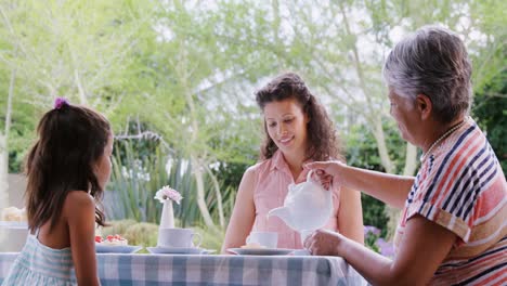 Mother,-daughter-and-granny-having-tea-in-the-garden-4K-4k