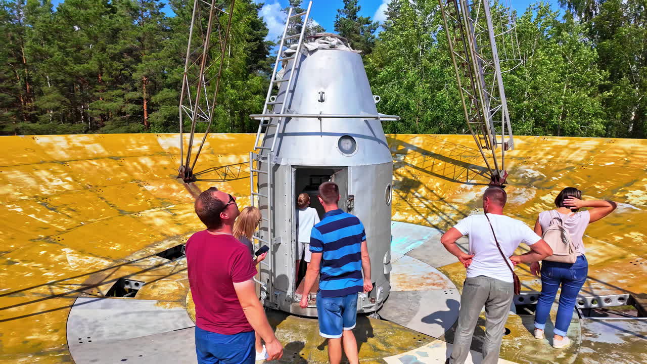 People exploring a space capsule exhibit outdoors