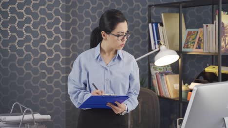 Worker-woman-looking-at-computer-and-taking-notes-works-in-office.