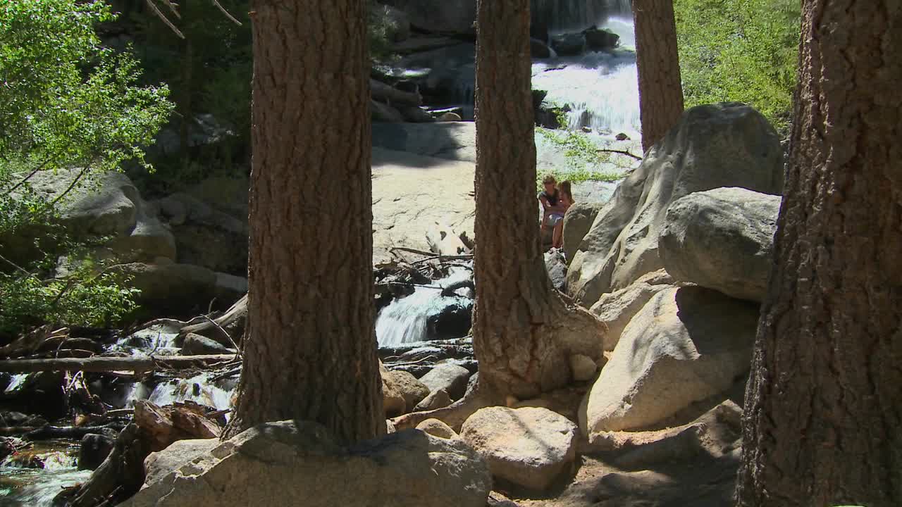 una madre y su hija disfrutan de un momento tranquilo junto a una cascada en un hermoso bosque