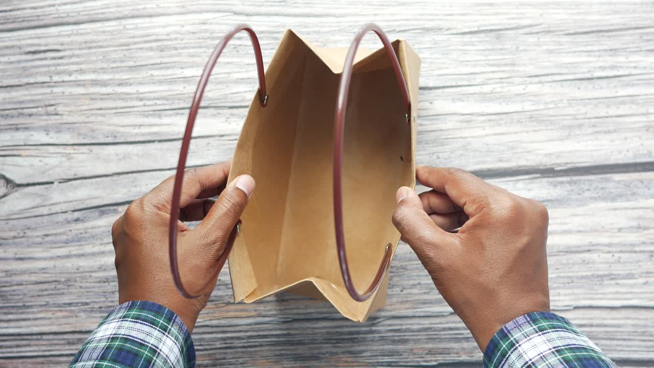 빈 갈색 종이 봉지를 들고 있는 사람