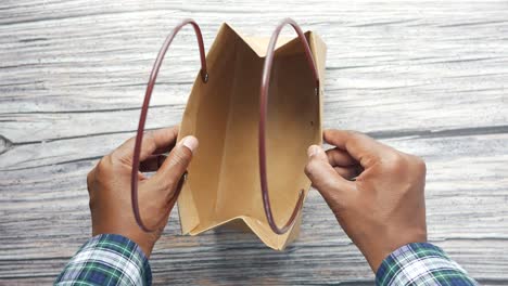 persona que sostiene una bolsa de papel marrón vacía
