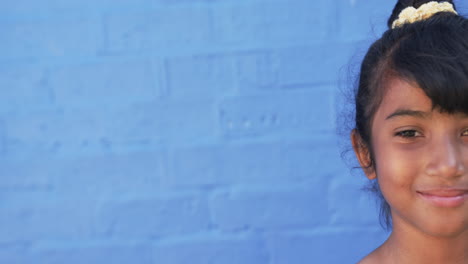 In-a-school-setting,-a-young-Hispanic-student-stands-before-a-blue-background-with-copy-space