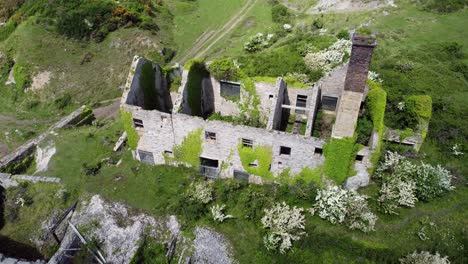 Abandoned-overgrown-ivy-covered-desolate-countryside-historical-Welsh-coastal-brick-factory-mill-aerial-birdseye-orbit-right-view