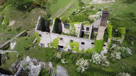 abandoned overgrown ivy covered desolate countryside historical welsh coastal brick factory mill aerial birdseye orbit right view