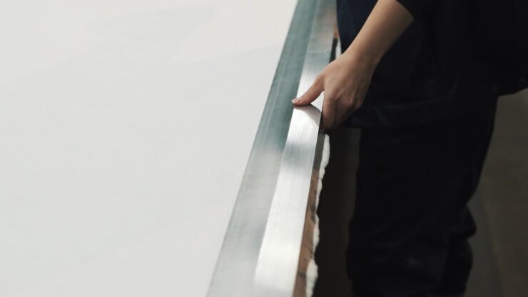 Close-up of female hands drawing a line for cutting on fabric under a ruler at a textile factory