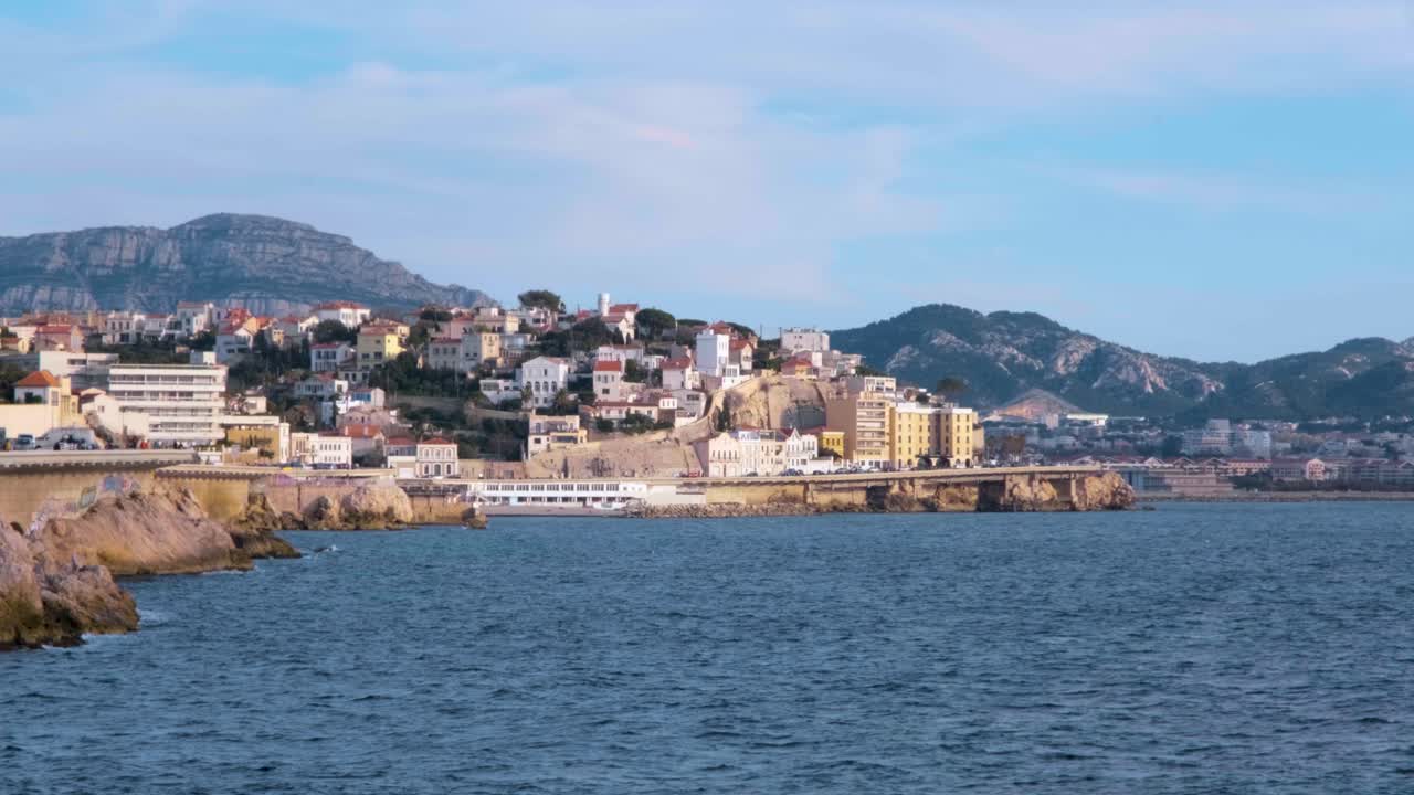La costa di Marsiglia si estende lungo il mare blu con le colline che si ergono dietro la corniche