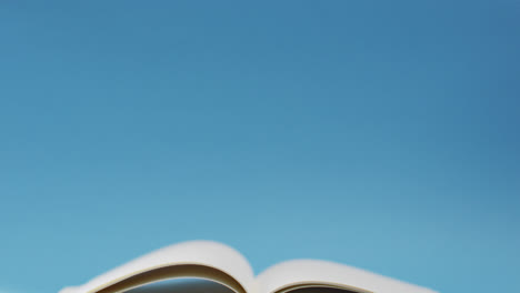 Video-of-open-book-with-navy-cover-on-desk-over-blue-background