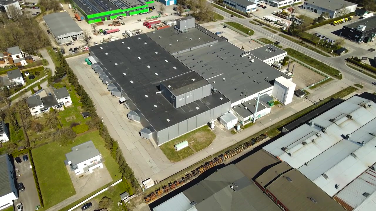 Area industriale con una fabbrica e magazzini a Saue, Estonia, caratterizzata da architettura moderna e infrastrutture circostanti, catturata da una prospettiva elevata in una giornata di sole